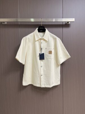 weigou_170816_0_6129b9fe42 P215 LV 桑蚕丝混纺短袖衬衫,本品采用桑蚕丝混纺梭织面料,经预缩与抗皱处理,布面带有细腻竖条肌理,触感清凉顺滑,兼具蚕丝的亲肤透气与棉的挺括耐用,适配夏季穿着。经典翻领采用平车包边工艺,线条利落挺括,贴合颈部曲线;门襟采用金属纽扣设计,牢固耐用,开合顺畅。胸前贴袋搭配真皮皮标装饰,皮质温润细腻,压印标识精致考究;后背字母与标识采用胶印工艺,油墨饱满厚实,边缘清晰锐利,经多次水洗测试无开裂脱落风险。肩部与侧缝采用双线缝合,走线均匀细密,衣身采用宽松落肩剪裁,适配多元身形。成衣经过预洗定型,米白色调柔和干净,兼具轻奢格调与日常实用性,适配通勤、休闲等多种穿搭场景。整体走线平直细腻,面料舒适柔软,颜色一致无色差 能与同款搭配营造时尚造型,驾驭各种场合,定制辅料,三标齐全,男女同款!尺码:S-XL S码 衣长70 胸围118 肩宽50 袖长 M码 衣长 胸围122 肩宽51 袖长28 L码 衣长73 胸围126 肩宽52 袖长 XL码 衣长 胸围130 肩宽53 袖长29“”BB61