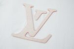 P110 LOUIS VUITTON 皮革刺绣标识短袖 面料：采用32支双纱精梳棉。 面料：螺纹采用1*1配套索罗娜。 辅料：浅粉面布切割复合羊皮，侧边带有人工油边工艺。高度还原原版LV标识辅料。 工艺：刺绣缝线，底部缝线定位后面上多缝一层使辅料与衣服牢牢凝固。 工艺：后服3D立体刺绣工艺,以品字母做为点点缀，整针数约为4800针。 本款T恤玩味2026秋冬秀场的视觉先锋，为轻盈棉质针织融入激光切割LV标识，其撞色毛毡底垫恰似品牌标志性VVN皮革的染色边缘，以考究笔触营造悬浮效果。背后的标识刺绣再添雅致一笔。 辅料：定制1：1洗水商标 辅料：定制1：1皮革标识 工艺：定制1：1刺绣标识 尺码：S-M-L-X 颜色：白 款号：86137-818