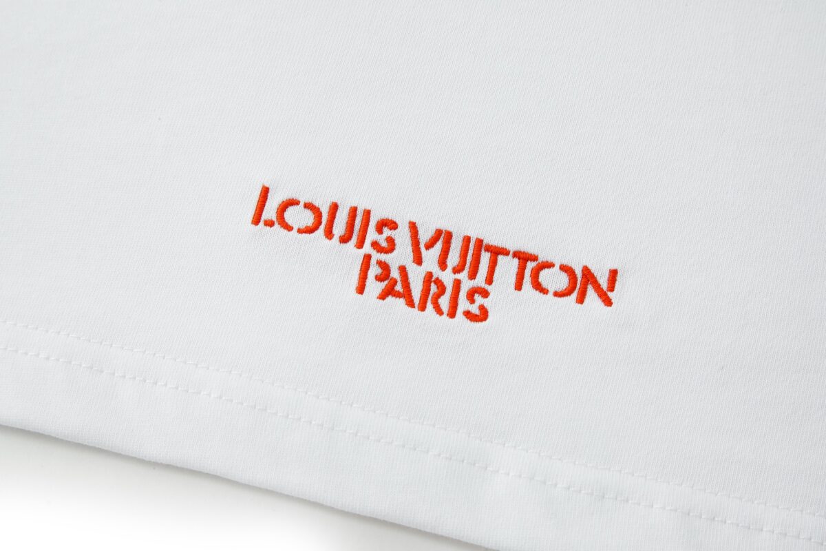 P110 LOUIS VUITTON 皮革刺绣标识短袖 面料：采用32支双纱精梳棉。 面料：螺纹采用1*1配套索罗娜。 辅料：浅粉面布切割复合羊皮，侧边带有人工油边工艺。高度还原原版LV标识辅料。 工艺：刺绣缝线，底部缝线定位后面上多缝一层使辅料与衣服牢牢凝固。 工艺：后服3D立体刺绣工艺,以品字母做为点点缀，整针数约为4800针。 本款T恤玩味2026秋冬秀场的视觉先锋，为轻盈棉质针织融入激光切割LV标识，其撞色毛毡底垫恰似品牌标志性VVN皮革的染色边缘，以考究笔触营造悬浮效果。背后的标识刺绣再添雅致一笔。 辅料：定制1：1洗水商标 辅料：定制1：1皮革标识 工艺：定制1：1刺绣标识 尺码：S-M-L-X 颜色：白 款号：86137-818