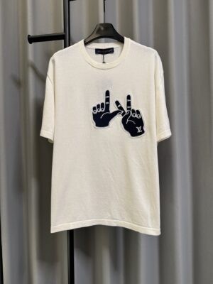 P155 【高端复刻】 𝐋𝐨𝐮𝐢𝐬 𝐕𝐮𝐢𝐭𝐭𝐨𝐧/路易 26SS lv手势刺绣针织短袖T恤（米白） LV 以趣味手势元素打造的创意系列短袖，用针织面料与立体刺绣工艺，打造兼具质感与个性的小众款。 🔹 面料与质感 核心面料：甄选LV 定制针织面料，布面细腻软糯，自带柔和哑光质感，上身轻薄透气，垂坠感优异，久穿不易起球变形。 穿着体验：面料亲肤透气，吸湿排汗性优异，夏季穿着清爽不闷汗；触感顺滑亲肤，不扎肤、不闷热，日常穿着舒适自在。 版型表现：合身直筒版型，修饰肩线与身形比例；圆领设计利落干练，自带简约高级氛围，适配多种穿搭场景。 🔹 工艺与细节 核心手势刺绣工艺： 胸口位置采用趣味手势刺绣，以藏蓝色为主体，搭配白色轮廓线，其中一只手上带有 LV 字母标识，刺绣针脚细密饱满，边缘无毛边，质感立体精致。在极简的米白色针织衣身上，这个创意手势刺绣是整件 T 恤的灵魂亮点。 细节做工： 领口采用罗纹收边，走线工整细密，反复穿着不易松垮变形； 袖口、下摆采用罗纹锁边，做工精细，不易脱线； 领标、洗水标等辅料齐全，完整还原正品配置，细节拉满。 Size：s/m/l/xl/