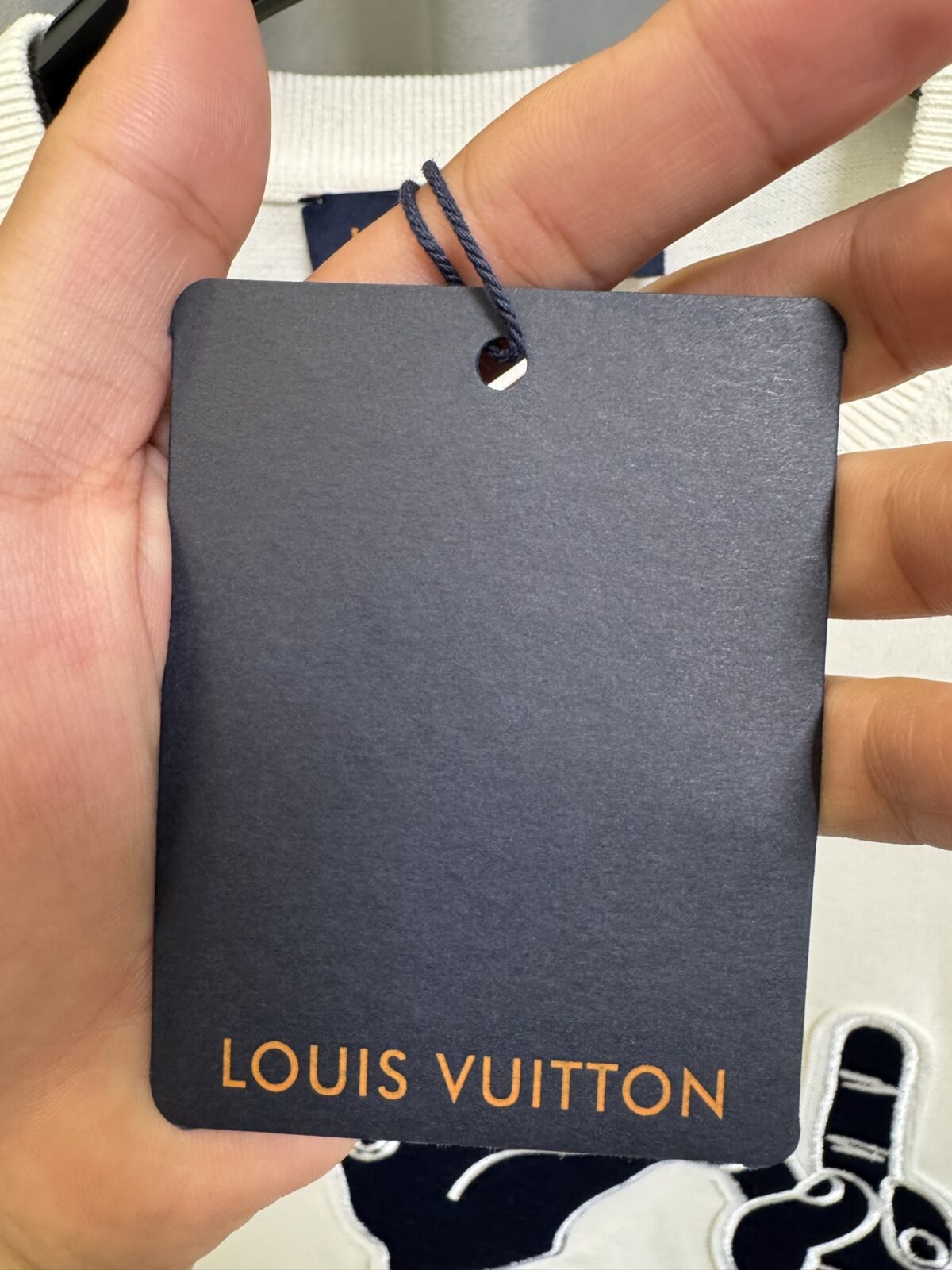 P155 【高端复刻】 𝐋𝐨𝐮𝐢𝐬 𝐕𝐮𝐢𝐭𝐭𝐨𝐧/路易 26SS lv手势刺绣针织短袖T恤（米白） LV 以趣味手势元素打造的创意系列短袖，用针织面料与立体刺绣工艺，打造兼具质感与个性的小众款。 🔹 面料与质感 核心面料：甄选LV 定制针织面料，布面细腻软糯，自带柔和哑光质感，上身轻薄透气，垂坠感优异，久穿不易起球变形。 穿着体验：面料亲肤透气，吸湿排汗性优异，夏季穿着清爽不闷汗；触感顺滑亲肤，不扎肤、不闷热，日常穿着舒适自在。 版型表现：合身直筒版型，修饰肩线与身形比例；圆领设计利落干练，自带简约高级氛围，适配多种穿搭场景。 🔹 工艺与细节 核心手势刺绣工艺： 胸口位置采用趣味手势刺绣，以藏蓝色为主体，搭配白色轮廓线，其中一只手上带有 LV 字母标识，刺绣针脚细密饱满，边缘无毛边，质感立体精致。在极简的米白色针织衣身上，这个创意手势刺绣是整件 T 恤的灵魂亮点。 细节做工： 领口采用罗纹收边，走线工整细密，反复穿着不易松垮变形； 袖口、下摆采用罗纹锁边，做工精细，不易脱线； 领标、洗水标等辅料齐全，完整还原正品配置，细节拉满。 Size：s/m/l/xl/