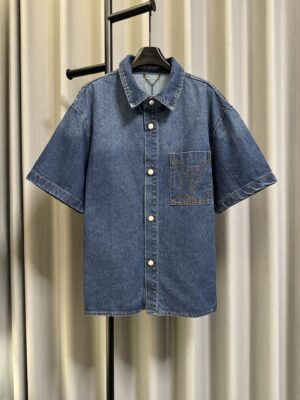 P155 【高端复刻】 LOUIS VUITTON/路易 26fw 素描刺绣LOGO短袖牛仔外套（蓝-另有配套短裤） 采用品牌定制牛仔高密提花面料，通体融入经典暗纹图案，经特殊工艺织造，纹理细腻立体，触感柔软顺滑，兼具良好的透气性与挺括度，久穿不易变形，彰显高端面料质感；经典古巴领设计，线条利落复古，修饰颈部线条，金属按扣开合，质感高级且穿脱便捷；胸前对称口袋设计，搭配金属铆钉点缀，细节精致考究，提升整体造型层次感；同系列短裤采用同款面料与暗纹设计，上下呼应，整体协调统一。 Size：s/m/l/xl