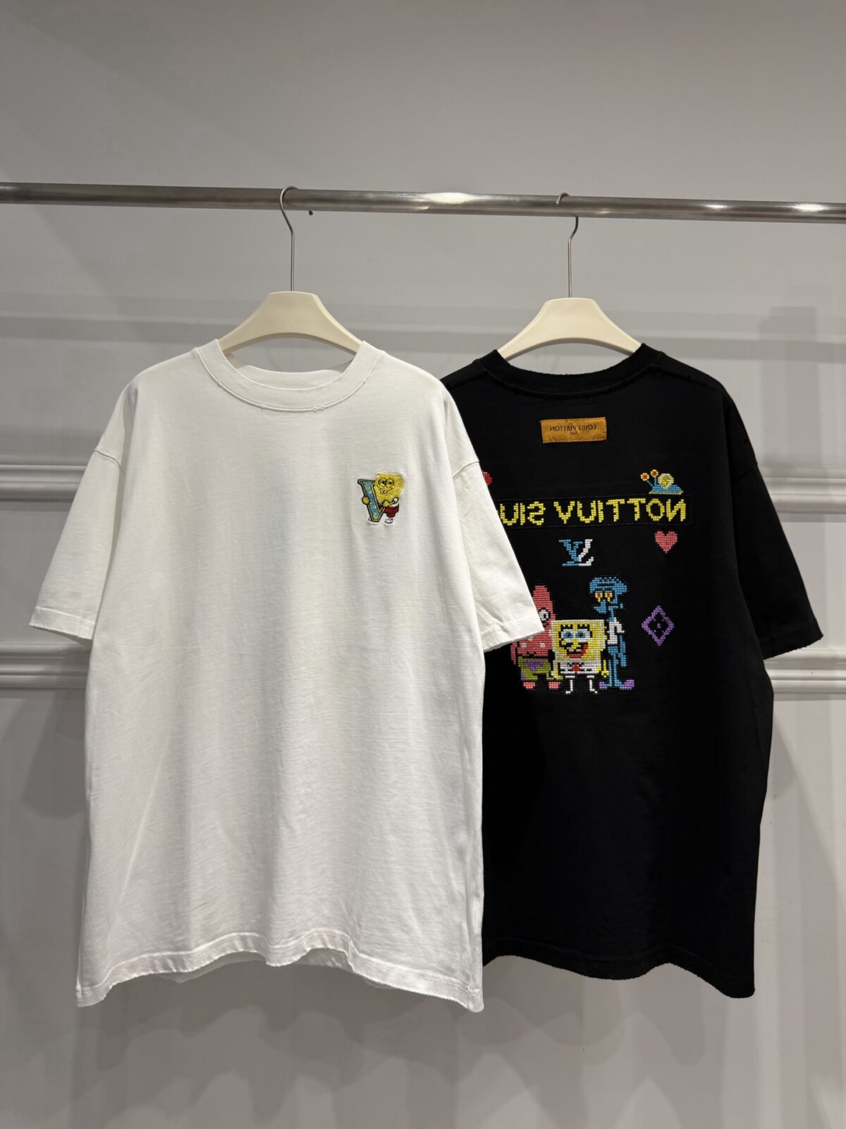 weigou_174587_0_dae0255148 P85 路易威登 LOUIS VUITTON × 海绵宝宝像素风刺绣联名限定T恤做旧圆领短袖 高品质 高工艺 细节拉满 经典重塑潮奢格调,正面海绵宝宝刺绣搭配LV品牌标识,趣味又吸睛;背面像素风派大星、章鱼哥组合印花,叠加LV Monogram元素,将童年回忆与奢侈美学完美融合。 甄选320克重磅纯棉面料,宽松落肩剪裁适配多元身形,磨边做旧工艺上身自带松弛街头感。不管是搭配牛仔裤打造日常出街造型,还是叠穿打造高街风,都能轻松拿捏。限量联名款自带收藏属性,是潮人衣橱里的刚需单品,轻松穿出专属个性态度。 尺码:S—XL 颜色:黑色 白色