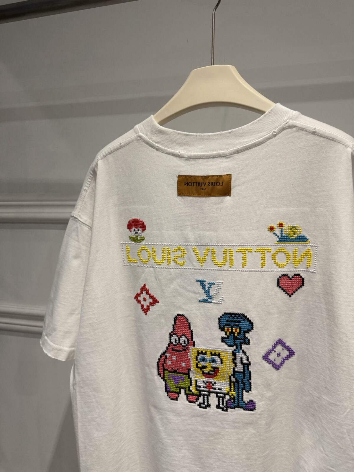 weigou_174587_8_43c4f1c111 P85 路易威登 LOUIS VUITTON × 海绵宝宝像素风刺绣联名限定T恤做旧圆领短袖 高品质 高工艺 细节拉满 经典重塑潮奢格调,正面海绵宝宝刺绣搭配LV品牌标识,趣味又吸睛;背面像素风派大星、章鱼哥组合印花,叠加LV Monogram元素,将童年回忆与奢侈美学完美融合。 甄选320克重磅纯棉面料,宽松落肩剪裁适配多元身形,磨边做旧工艺上身自带松弛街头感。不管是搭配牛仔裤打造日常出街造型,还是叠穿打造高街风,都能轻松拿捏。限量联名款自带收藏属性,是潮人衣橱里的刚需单品,轻松穿出专属个性态度。 尺码:S—XL 颜色:黑色 白色