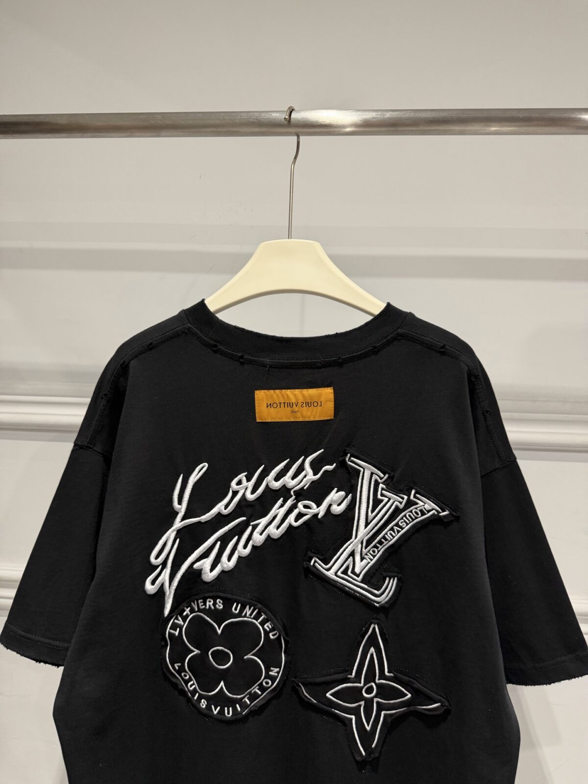 P80 Louis Vuitton路易威登LV新款涂鸦重工刺绣短袖做旧T恤 这件路易威登将品牌经典老花元素以涂鸦风刺绣重新演绎，自带街头潮流气场。正面低调的四叶花刺绣暗藏巧思，背面则是手写体品牌标识与多种Monogram图腾的组合刺绣层次丰富 磨破做旧工艺又个性吸睛。 甄选320高克重纯棉面料，触感柔软亲肤，上身垂坠有型，久穿也不易变形。宽松落肩版型对身材包容性极强，男女同款适配情侣穿搭，搭配工装裤、破洞牛仔或阔腿卫裤都超有范儿。 作为衣橱里的“百搭王”，它既能驾驭日常出街，也能撑起潮酷造型，是兼顾质感与个性的高阶潮流单品，懂的朋友别错过！ 尺码：S—XL 颜色：黑色 白色