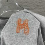 P75 Herme*爱马仕* 2026 春夏新款 经典橙色刺绣 定制双纱平纹纯棉面料 短袖T恤 男女同款 颜色 ：黑色 白色 花灰色 尺码： S （90-130斤） M （120-150斤） L （140-165斤） XL （160-180斤） XXL （180-210斤）