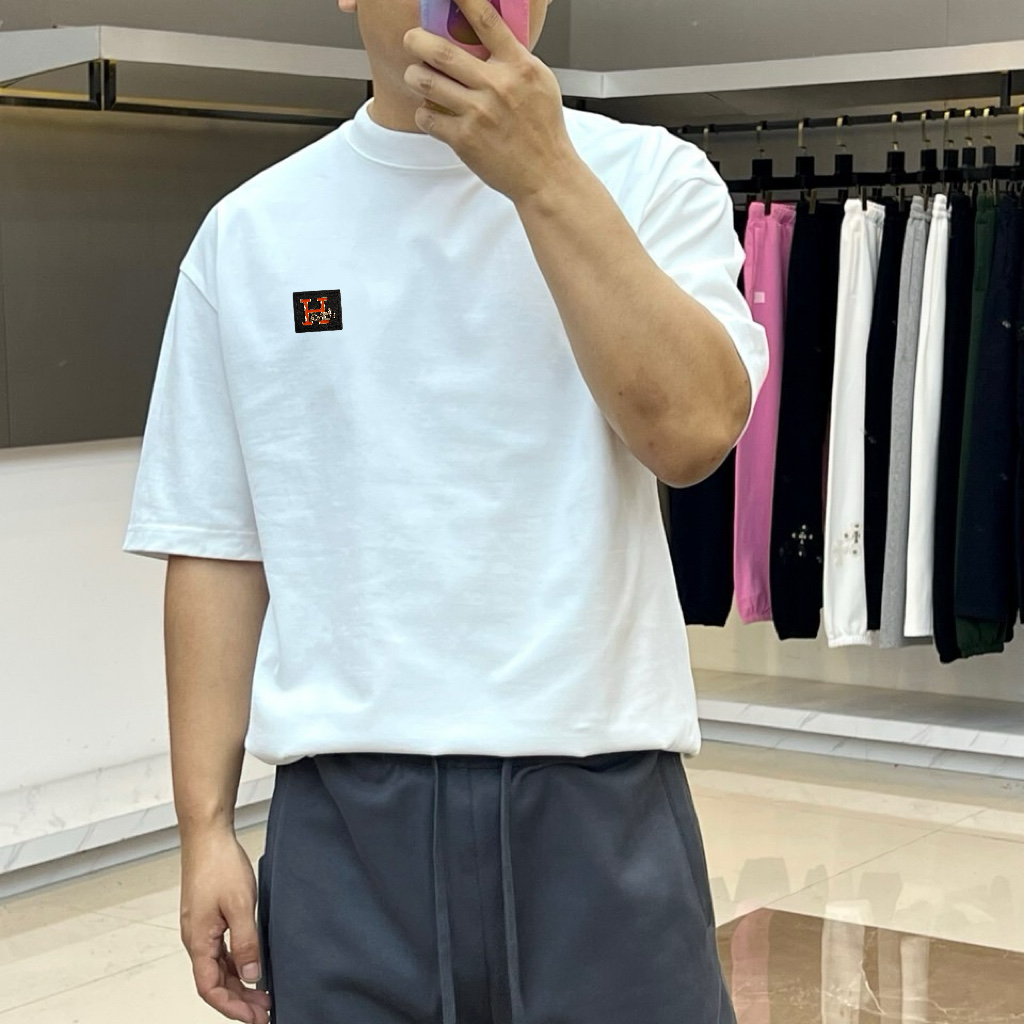 P75 爱马仕 2026春夏新品经典短袖T恤，延续品牌标志性的简约美学与法式松弛感，以纯色为底色，左胸点缀小巧精致刺绣，精致不张扬，诠释低调高级的都市格调。宽松廓形剪裁，落肩设计搭配微阔下摆，包容各种身形，营造随性自在的穿着体验，无论是单穿还是叠搭皆能轻松驾驭。面料甄选高支棉质，触感柔软亲肤，透气性佳，适合春夏日常通勤、周末出游或轻社交场合。极简线条与自然垂坠感赋予衣身流动韵律，细节处彰显匠心工艺，下摆保留原厂吊牌，传递新品首发质感。这款T恤不仅是衣橱基础款，更是风格表达的点睛之笔——不喧哗，自有声。2026春夏，让爱与自由在衣襟间悄然绽放，穿出属于你的温柔力量与都市从容。S- XXL（模特173，140斤上身M码）