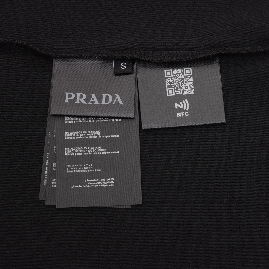 P65 PRADA普拉达2026ss新款胸前三角标情侣休闲短袖T恤 👑最高版本！280克、32支双纱面料！定制经典三角标！ 辅料：开模原版过鉴定领标➕100%真丝洗水标。正品代购级原版吊牌➕配套吊绳➕3D吊粒➕原版包装袋 工艺：原版一致走线！袖窿对版手法 最高版本！无数次的打版 百分百还原正品品相！ 正确版本 男女同款 超级显眼 超级好看 超级大气！ 颜色：黑色 白色 尺码：Xs-L