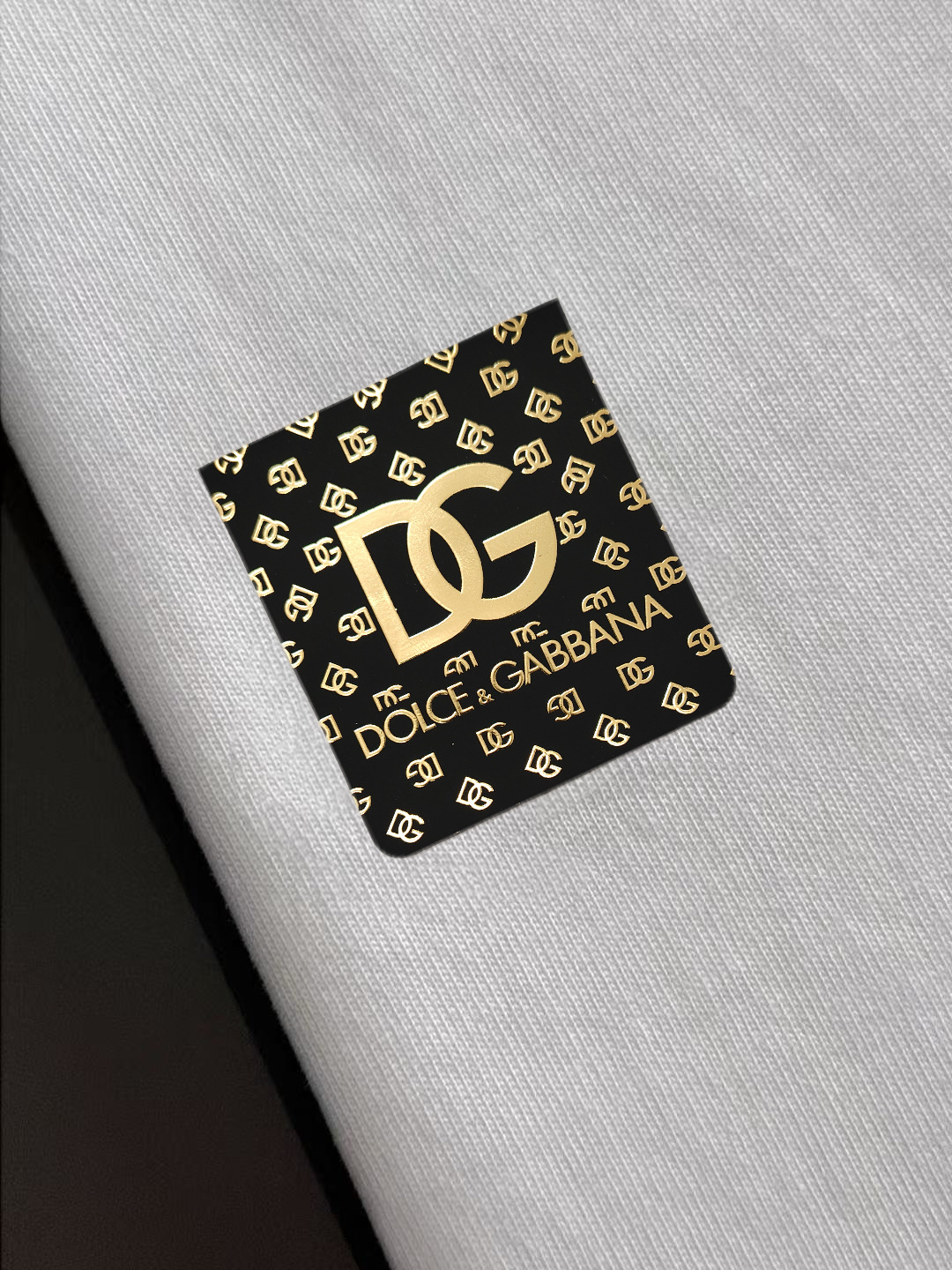 P75 DG专柜同款圆领短袖T恤 定制棉质面料 ！采用品牌Logo标志皮牌设计！ 立体感强！使整体高透气和柔软性的质感更加凸显，饱满的棉质感引起极度舒适。高端人士必备单品，原厂辅料三标齐全！男女同款！ 颜色：黑色 白色 尺码：S-xxL
