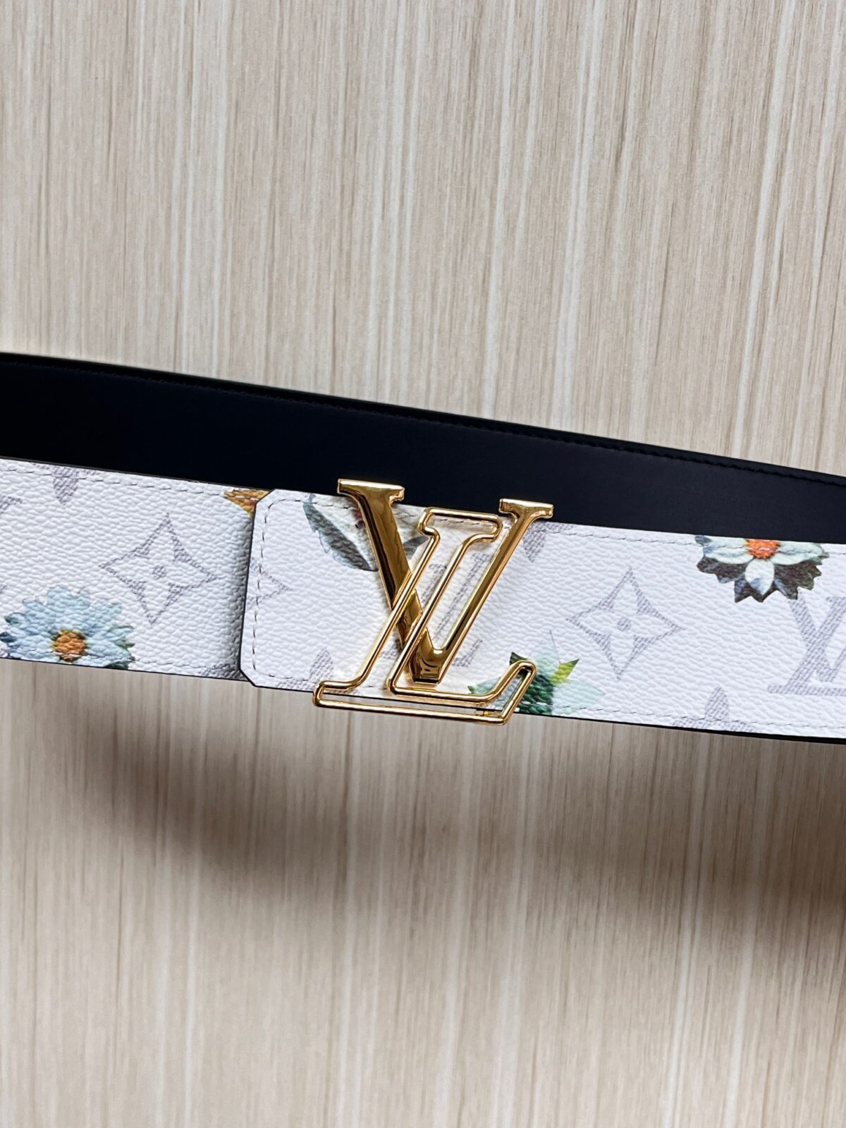 P150 当季新款，LV Initiales Monogram Flower系列40毫米可翻转腰带重新诠释了经典的LV标志，以唤起运动和情感的花纹。在画布一侧，Monogram通过添加白色和金色调的花朵，生动地描绘了每一片花瓣，赋予了它新的生命。白色的皮革背面同样优雅。 白花印百合花。