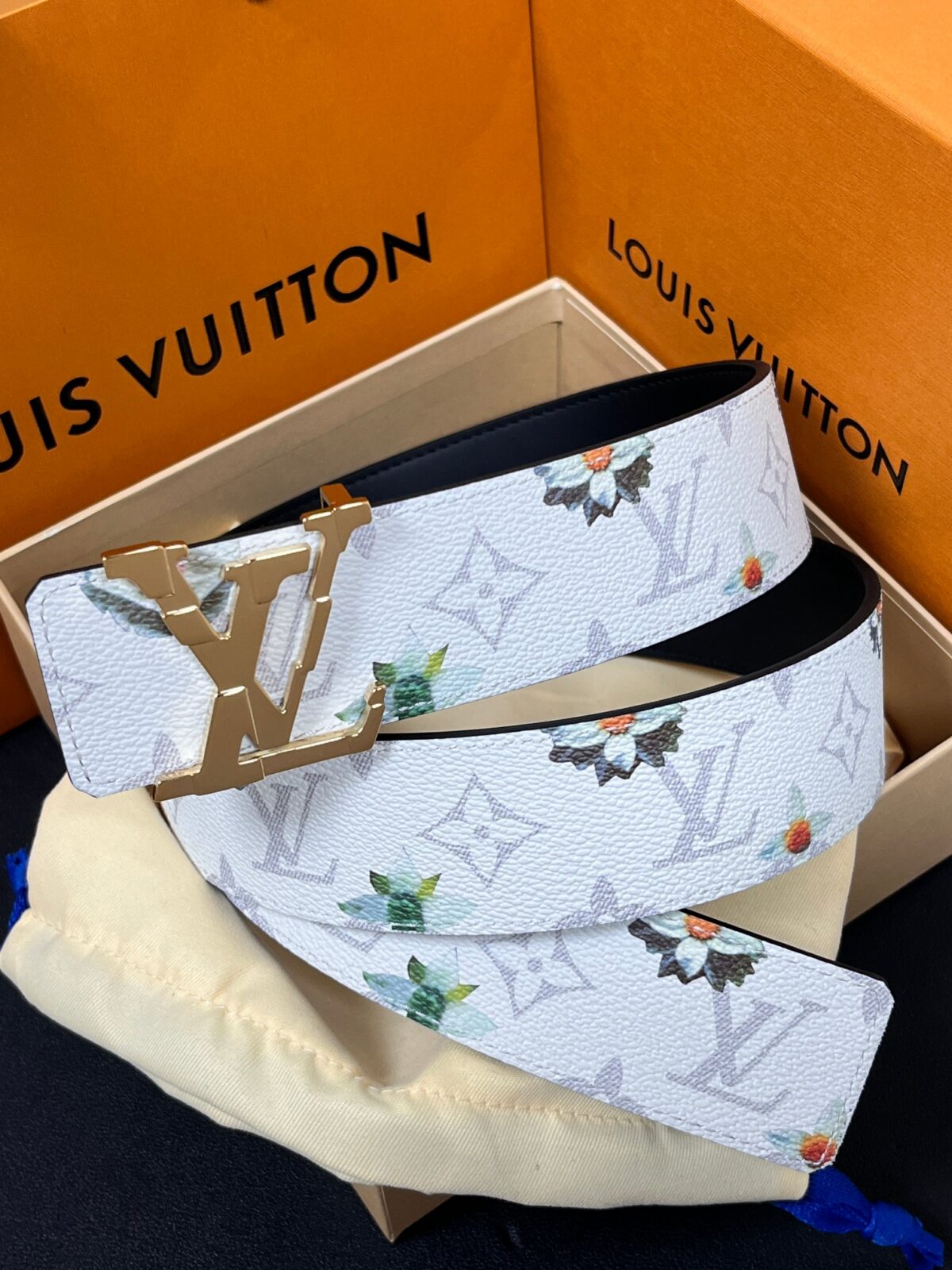 P150 当季新款，LV Initiales Monogram Flower系列40毫米可翻转腰带重新诠释了经典的LV标志，以唤起运动和情感的花纹。在画布一侧，Monogram通过添加白色和金色调的花朵，生动地描绘了每一片花瓣，赋予了它新的生命。白色的皮革背面同样优雅。 白花印百合花