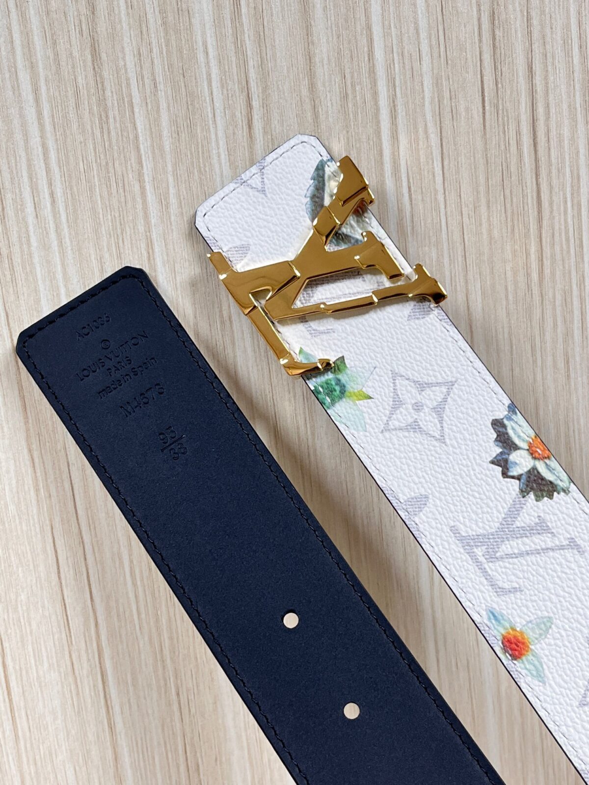 P150 当季新款，LV Initiales Monogram Flower系列40毫米可翻转腰带重新诠释了经典的LV标志，以唤起运动和情感的花纹。在画布一侧，Monogram通过添加白色和金色调的花朵，生动地描绘了每一片花瓣，赋予了它新的生命。白色的皮革背面同样优雅。 白花印百合花