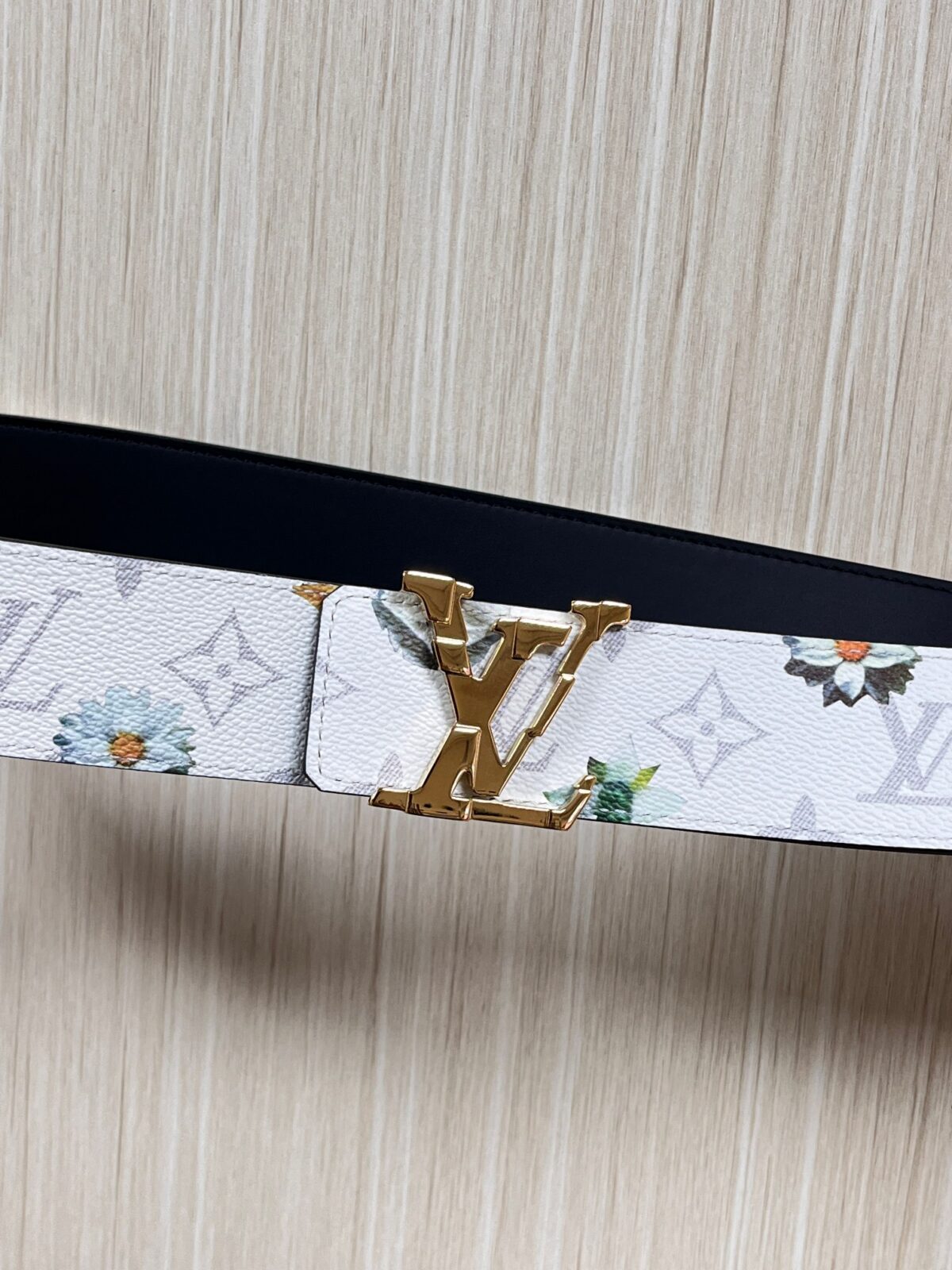 P150 当季新款，LV Initiales Monogram Flower系列40毫米可翻转腰带重新诠释了经典的LV标志，以唤起运动和情感的花纹。在画布一侧，Monogram通过添加白色和金色调的花朵，生动地描绘了每一片花瓣，赋予了它新的生命。白色的皮革背面同样优雅。 白花印百合花