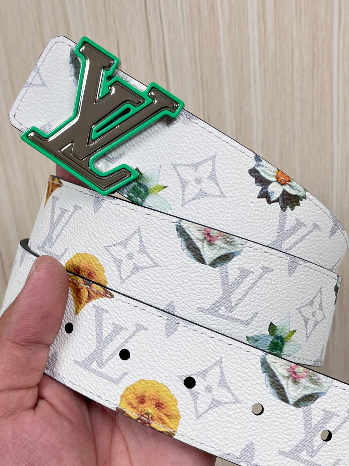 P150 当季新款，LV Initiales Monogram Flower系列40毫米可翻转腰带重新诠释了经典的LV标志，以唤起运动和情感的花纹。在画布一侧，Monogram通过添加白色和金色调的花朵，生动地描绘了每一片花瓣，赋予了它新的生命。白色的皮革背面同样优雅。 白花印百合花
