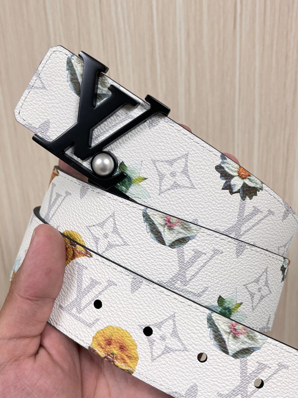 P150 当季新款，LV Initiales Monogram Flower系列40毫米可翻转腰带重新诠释了经典的LV标志，以唤起运动和情感的花纹。在画布一侧，Monogram通过添加白色和金色调的花朵，生动地描绘了每一片花瓣，赋予了它新的生命。白色的皮革背面同样优雅。 白花印百合花