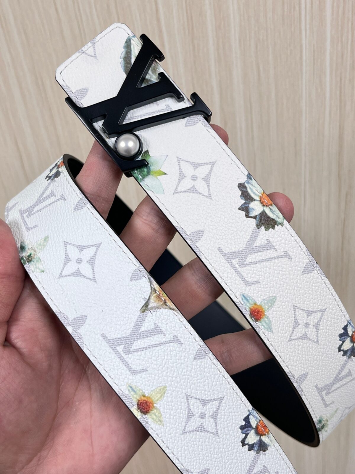 P150 当季新款，LV Initiales Monogram Flower系列40毫米可翻转腰带重新诠释了经典的LV标志，以唤起运动和情感的花纹。在画布一侧，Monogram通过添加白色和金色调的花朵，生动地描绘了每一片花瓣，赋予了它新的生命。白色的皮革背面同样优雅。 白花印百合花