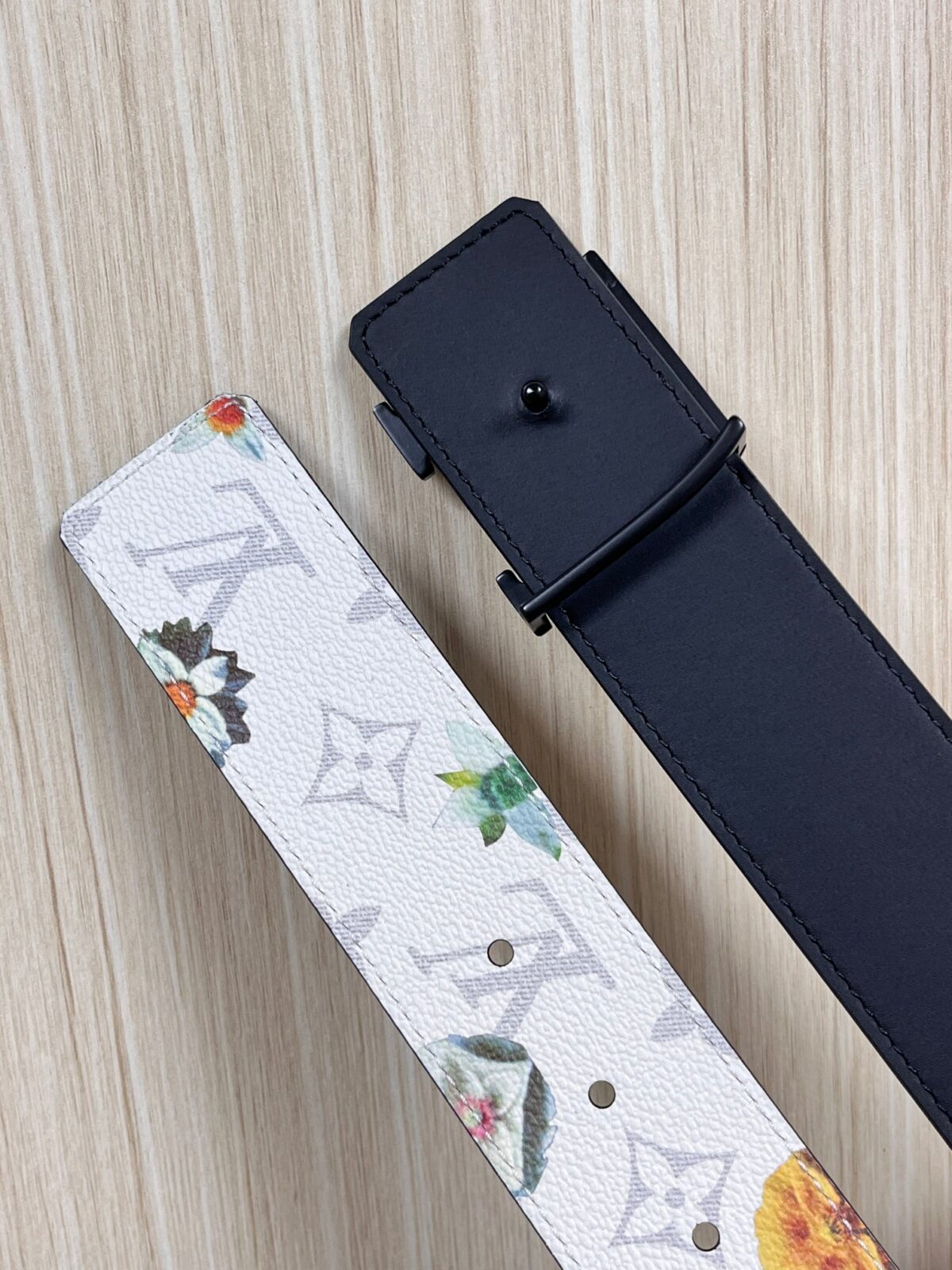 P150 当季新款，LV Initiales Monogram Flower系列40毫米可翻转腰带重新诠释了经典的LV标志，以唤起运动和情感的花纹。在画布一侧，Monogram通过添加白色和金色调的花朵，生动地描绘了每一片花瓣，赋予了它新的生命。白色的皮革背面同样优雅。 白花印百合花