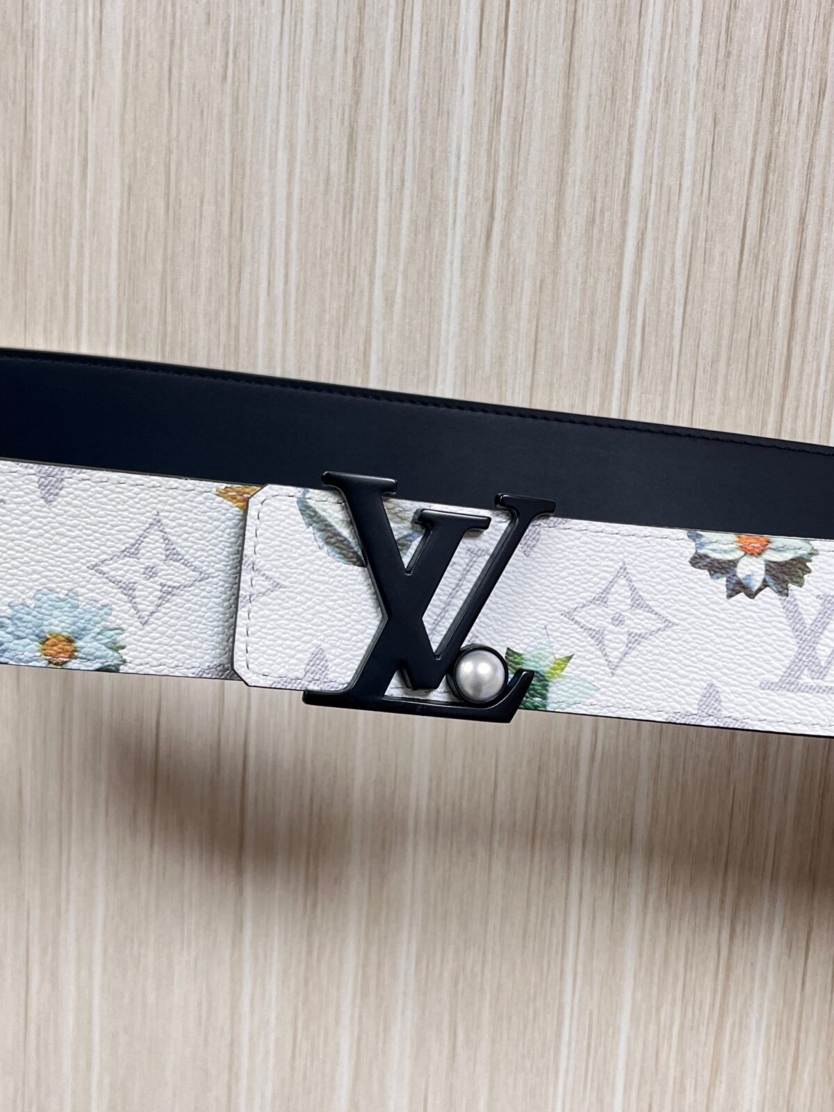 P150 当季新款，LV Initiales Monogram Flower系列40毫米可翻转腰带重新诠释了经典的LV标志，以唤起运动和情感的花纹。在画布一侧，Monogram通过添加白色和金色调的花朵，生动地描绘了每一片花瓣，赋予了它新的生命。白色的皮革背面同样优雅。 白花印百合花