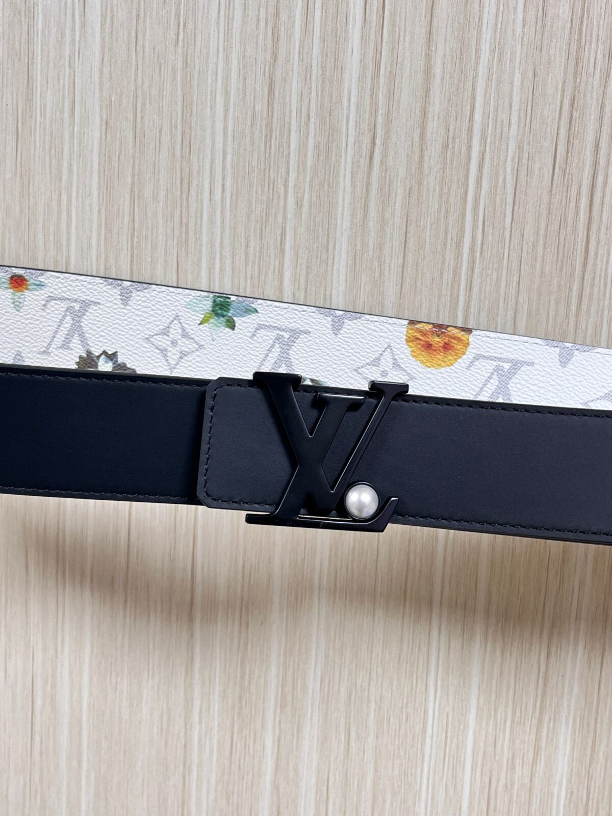 P150 当季新款，LV Initiales Monogram Flower系列40毫米可翻转腰带重新诠释了经典的LV标志，以唤起运动和情感的花纹。在画布一侧，Monogram通过添加白色和金色调的花朵，生动地描绘了每一片花瓣，赋予了它新的生命。白色的皮革背面同样优雅。 白花印百合花