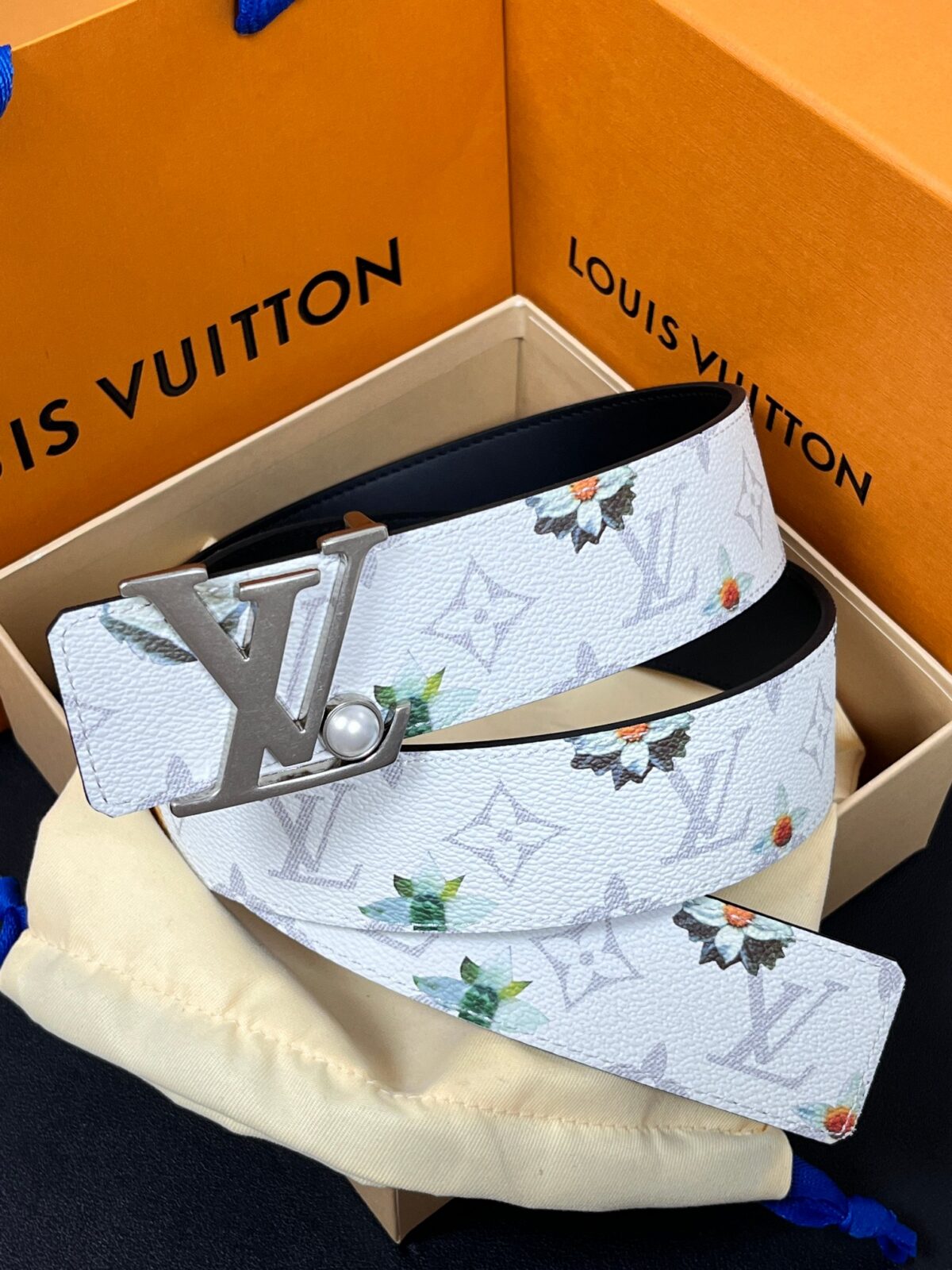 P150 当季新款，LV Initiales Monogram Flower系列40毫米可翻转腰带重新诠释了经典的LV标志，以唤起运动和情感的花纹。在画布一侧，Monogram通过添加白色和金色调的花朵，生动地描绘了每一片花瓣，赋予了它新的生命。白色的皮革背面同样优雅。 白花印百合花