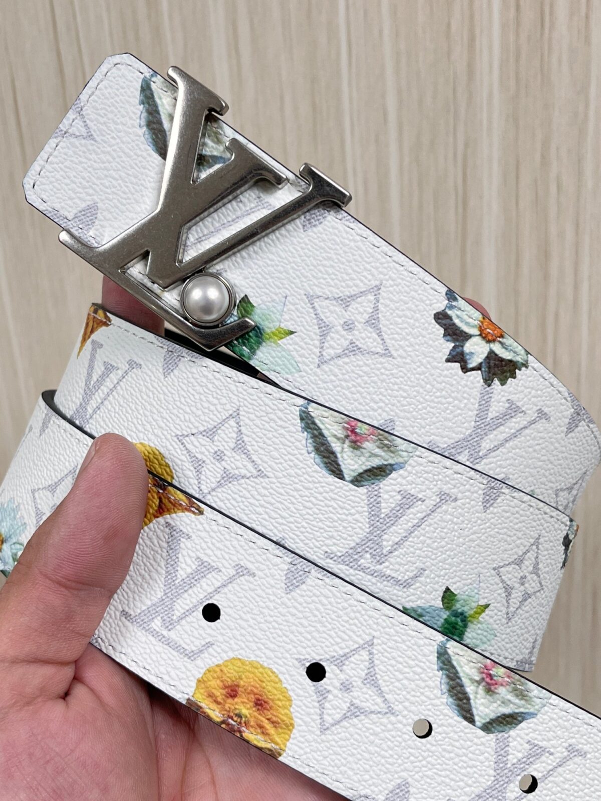P150 当季新款，LV Initiales Monogram Flower系列40毫米可翻转腰带重新诠释了经典的LV标志，以唤起运动和情感的花纹。在画布一侧，Monogram通过添加白色和金色调的花朵，生动地描绘了每一片花瓣，赋予了它新的生命。白色的皮革背面同样优雅。 白花印百合花
