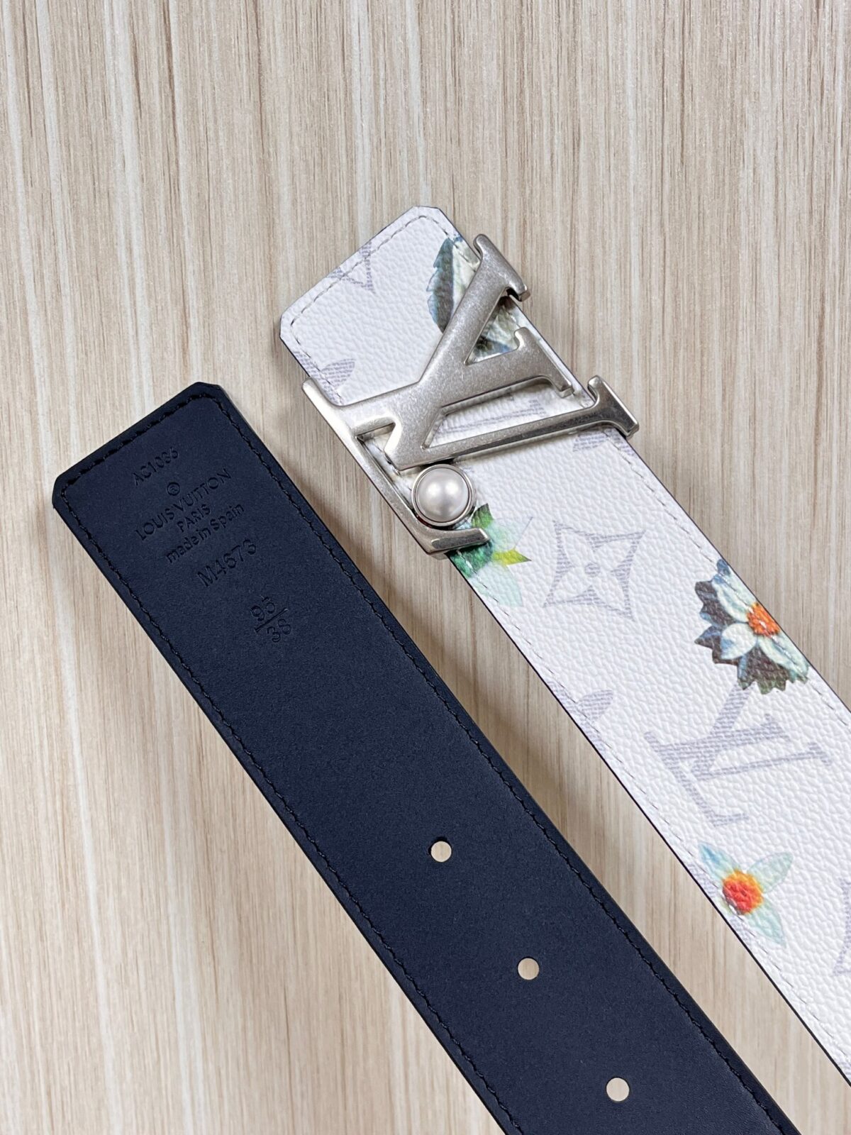 P150 当季新款，LV Initiales Monogram Flower系列40毫米可翻转腰带重新诠释了经典的LV标志，以唤起运动和情感的花纹。在画布一侧，Monogram通过添加白色和金色调的花朵，生动地描绘了每一片花瓣，赋予了它新的生命。白色的皮革背面同样优雅。 白花印百合花