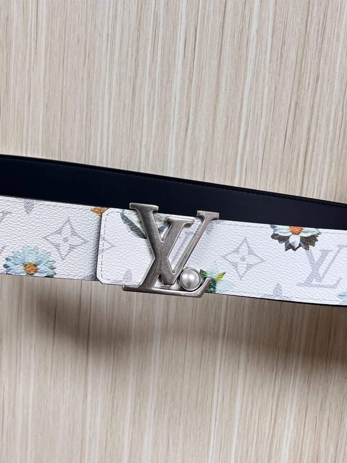 P150 当季新款，LV Initiales Monogram Flower系列40毫米可翻转腰带重新诠释了经典的LV标志，以唤起运动和情感的花纹。在画布一侧，Monogram通过添加白色和金色调的花朵，生动地描绘了每一片花瓣，赋予了它新的生命。白色的皮革背面同样优雅。 白花印百合花