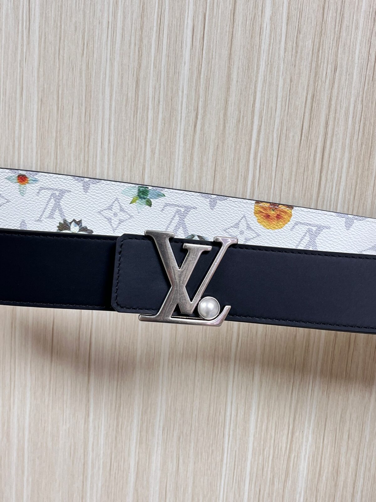 P150 当季新款，LV Initiales Monogram Flower系列40毫米可翻转腰带重新诠释了经典的LV标志，以唤起运动和情感的花纹。在画布一侧，Monogram通过添加白色和金色调的花朵，生动地描绘了每一片花瓣，赋予了它新的生命。白色的皮革背面同样优雅。 白花印百合花