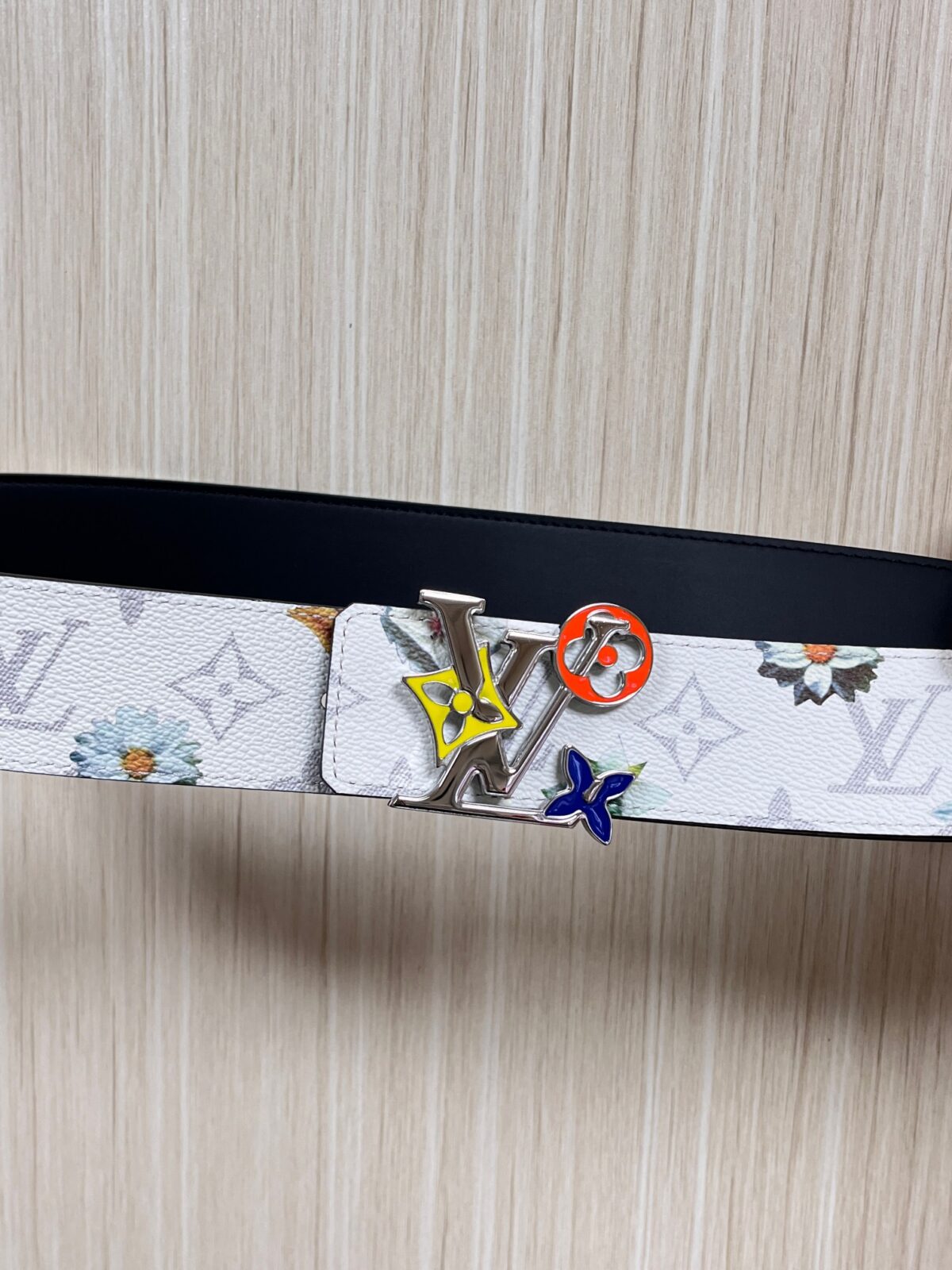 P150 当季新款，LV Initiales Monogram Flower系列40毫米可翻转腰带重新诠释了经典的LV标志，以唤起运动和情感的花纹。在画布一侧，Monogram通过添加白色和金色调的花朵，生动地描绘了每一片花瓣，赋予了它新的生命。白色的皮革背面同样优雅。 白花印百合花。