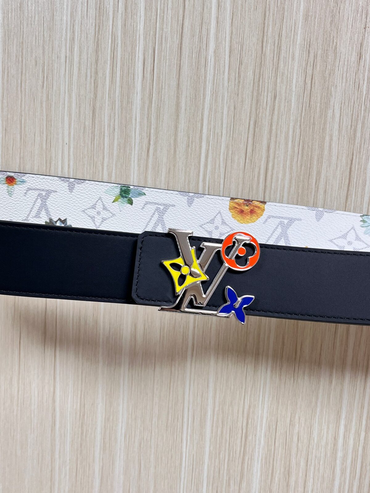 P150 当季新款，LV Initiales Monogram Flower系列40毫米可翻转腰带重新诠释了经典的LV标志，以唤起运动和情感的花纹。在画布一侧，Monogram通过添加白色和金色调的花朵，生动地描绘了每一片花瓣，赋予了它新的生命。白色的皮革背面同样优雅。 白花印百合花。