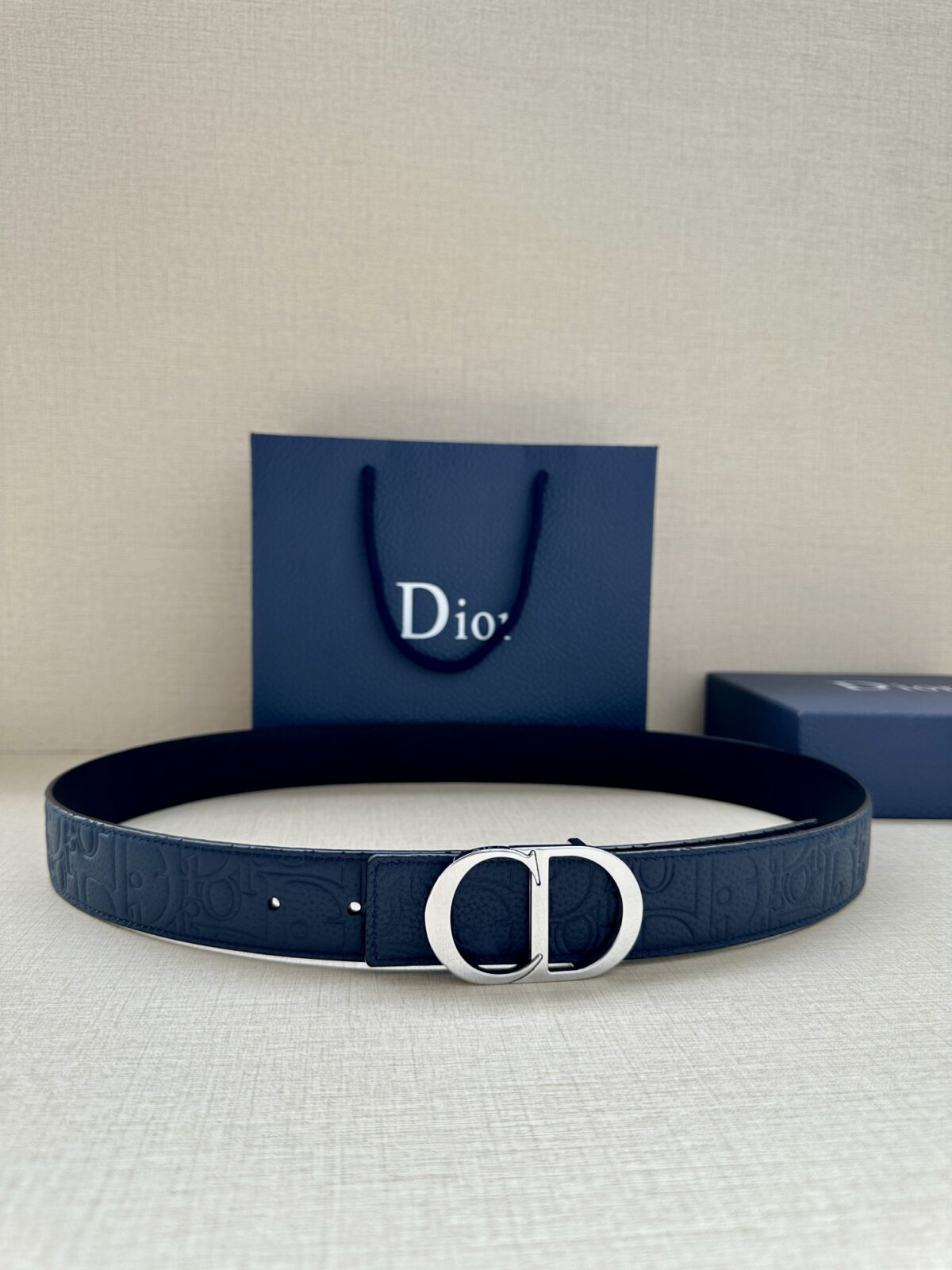 Dior Gravity 印花效果皮革，以牛皮革融合压花工艺，演绎经典的 Oblique 印花，展现 Dior 的精湛工艺。另一面则采用同色调光滑牛皮革。长度可调节，可搭配各式 35 毫米腰带扣。 /