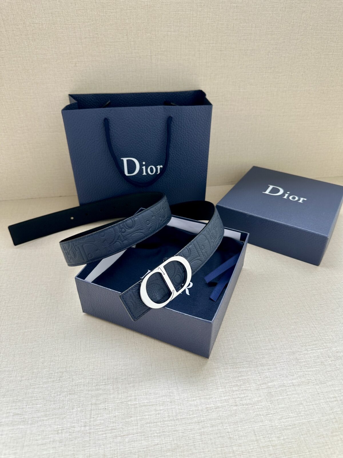 Dior Gravity 印花效果皮革，以牛皮革融合压花工艺，演绎经典的 Oblique 印花，展现 Dior 的精湛工艺。另一面则采用同色调光滑牛皮革。长度可调节，可搭配各式 35 毫米腰带扣。 /