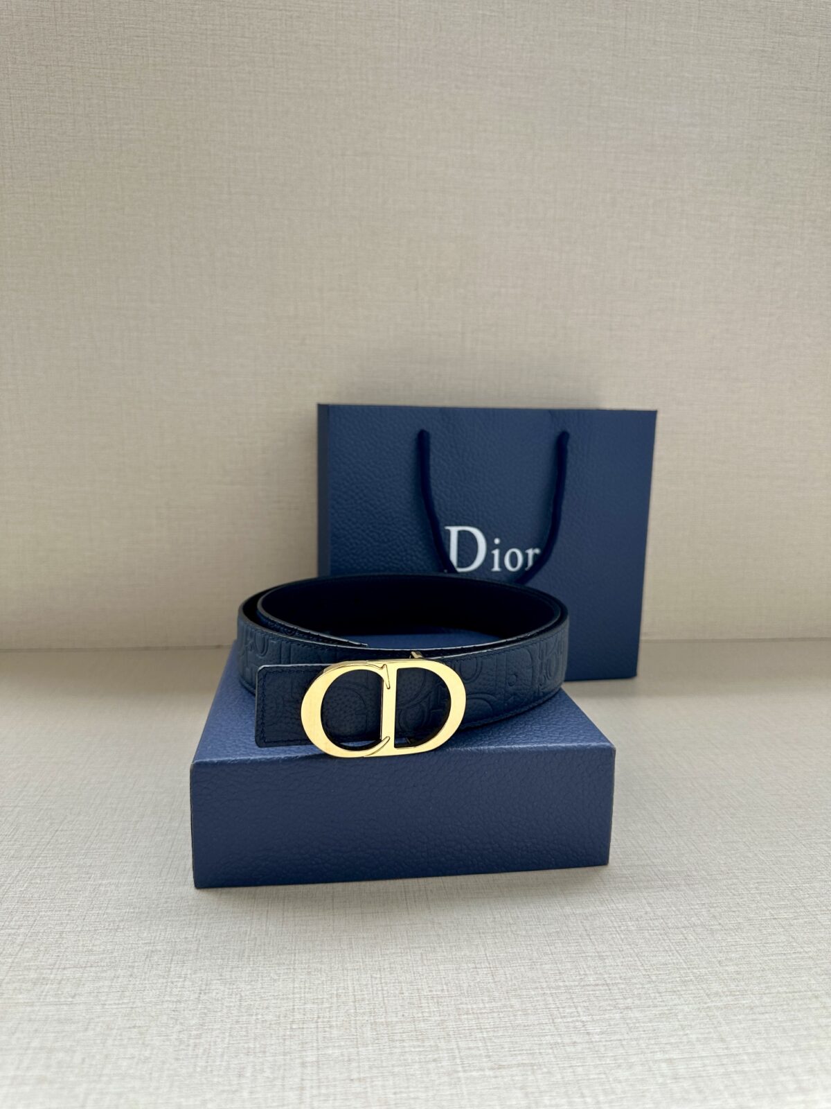 Dior Gravity 印花效果皮革，以牛皮革融合压花工艺，演绎经典的 Oblique 印花，展现 Dior 的精湛工艺。另一面则采用同色调光滑牛皮革。长度可调节，可搭配各式 35 毫米腰带扣。 /