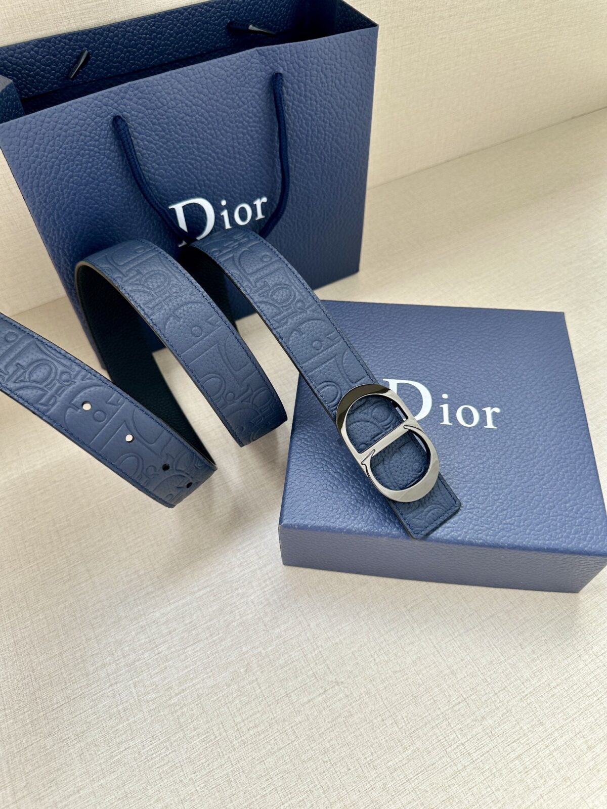 Dior Gravity 印花效果皮革，以牛皮革融合压花工艺，演绎经典的 Oblique 印花，展现 Dior 的精湛工艺。另一面则采用同色调光滑牛皮革。长度可调节，可搭配各式 35 毫米腰带扣。 /