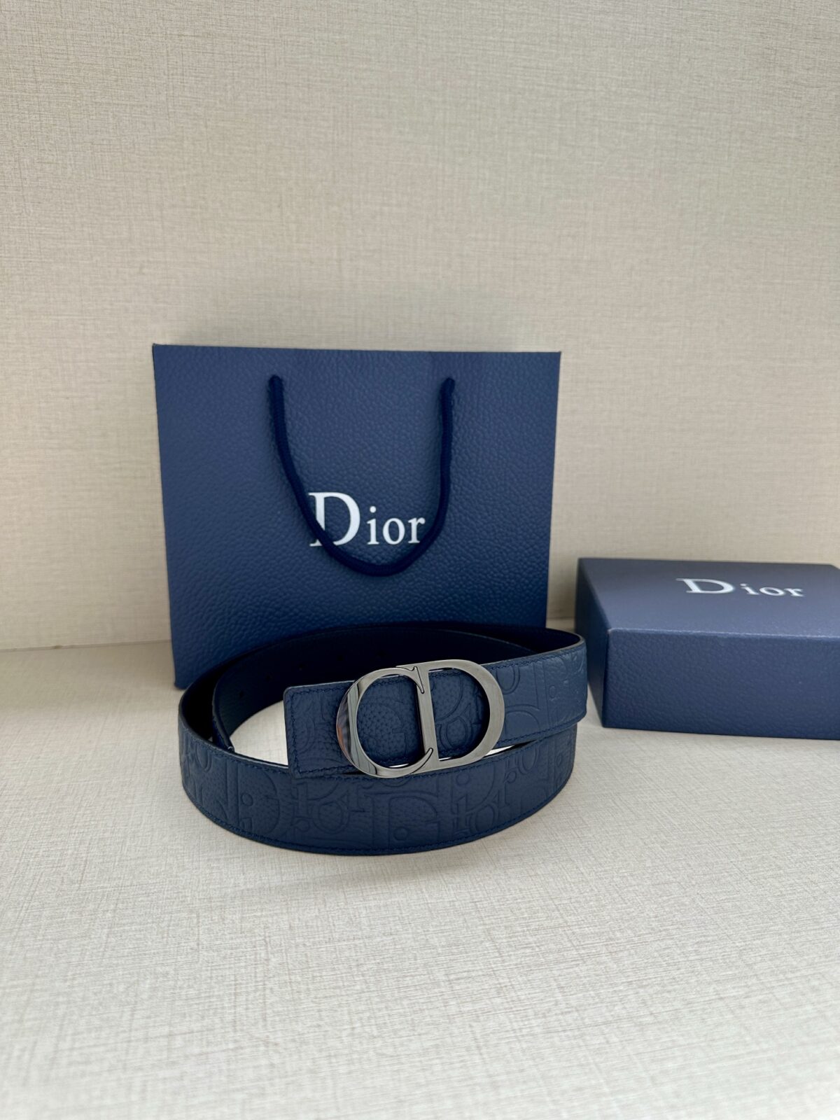 Dior Gravity 印花效果皮革，以牛皮革融合压花工艺，演绎经典的 Oblique 印花，展现 Dior 的精湛工艺。另一面则采用同色调光滑牛皮革。长度可调节，可搭配各式 35 毫米腰带扣。 /