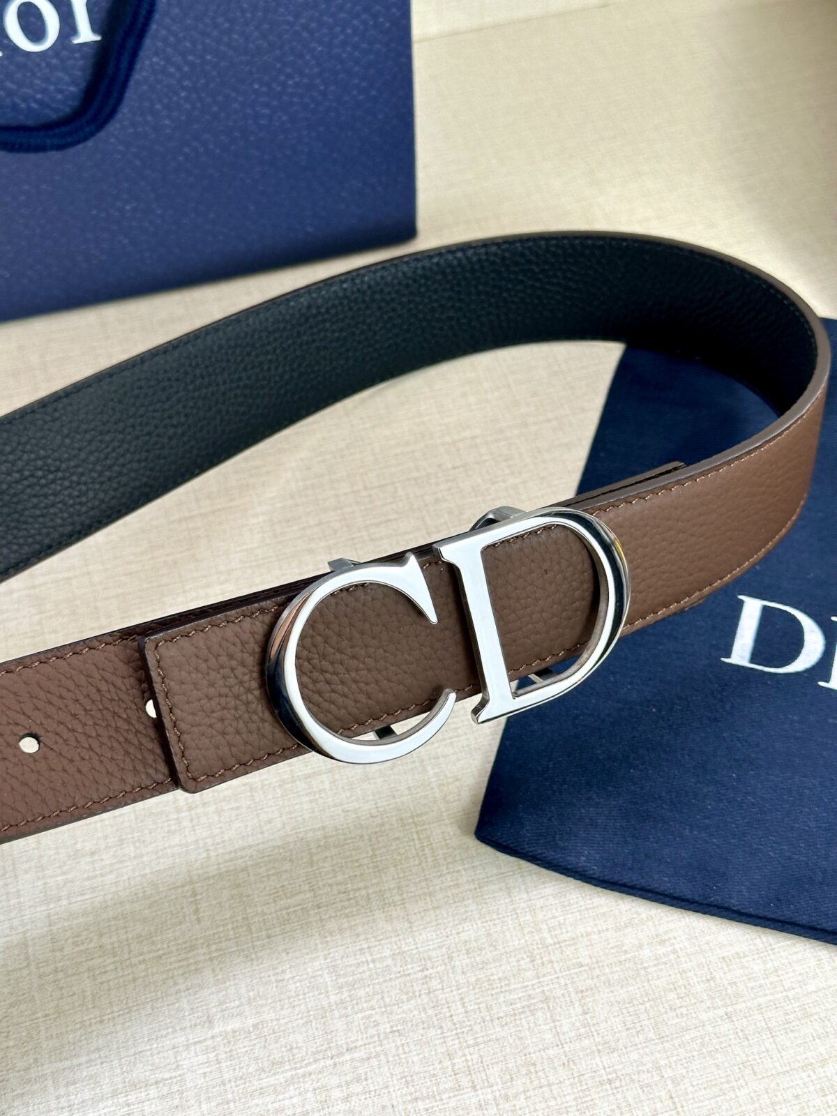 Dior 这款双面腰带结合典雅气质与摩登风范。双面均采用粒面牛皮革精心制作，一面为黑色，另一面为橄榄绿色、可搭配各式 35 毫米腰带扣，更添精致，打造富有个性特色的配饰，时尚百搭。 /