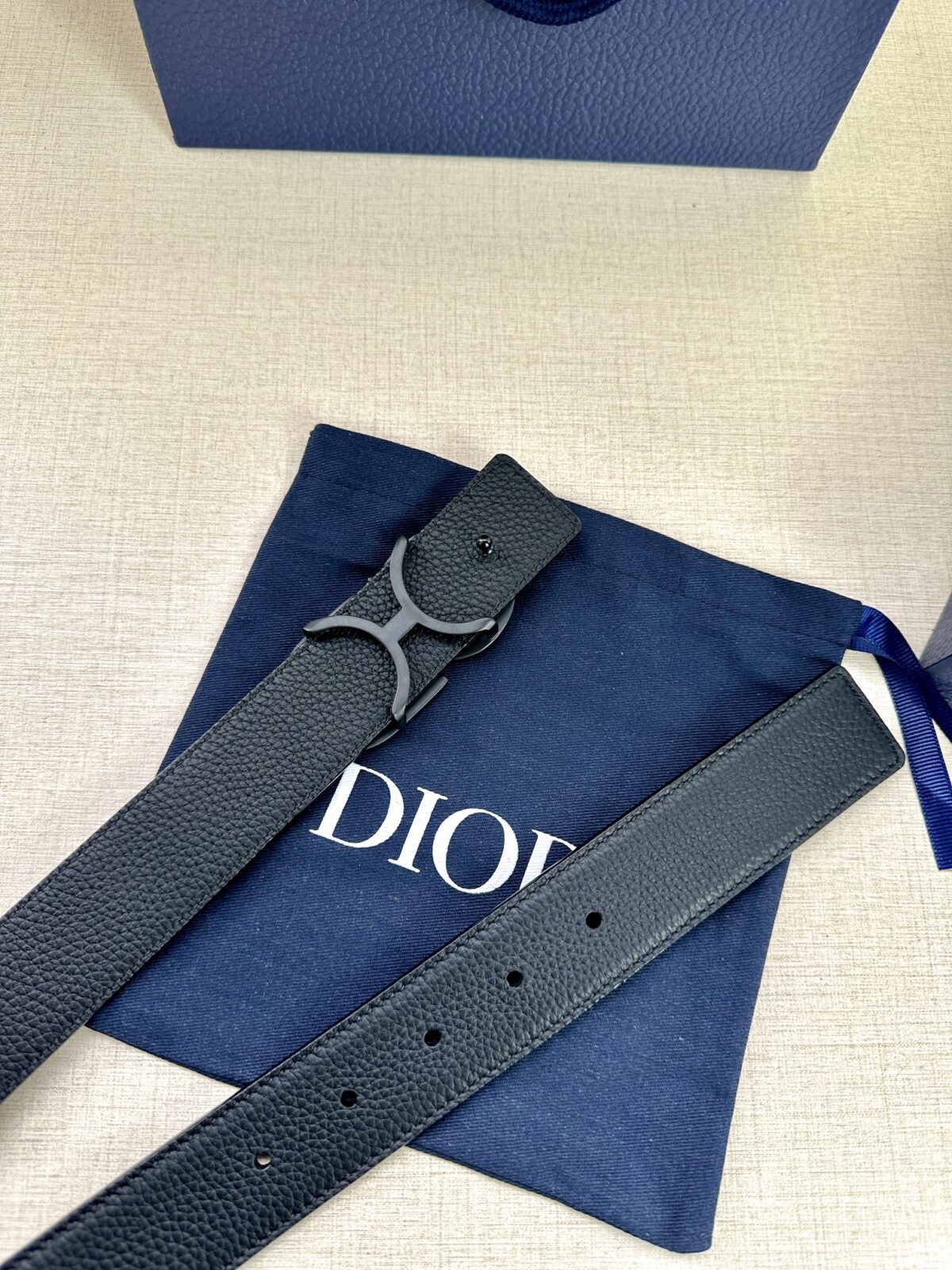 Dior 这款双面腰带结合典雅气质与摩登风范。双面均采用粒面牛皮革精心制作，一面为黑色，另一面为中国红、可搭配各式 35 毫米腰带扣，更添精致，打造富有个性特色的配饰，时尚百搭。 /